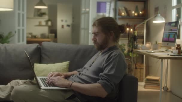 Zoom Tiro Jovem Barbudo Descansando Sofá Usando Laptop Enquanto Navega — Vídeo de Stock