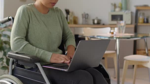家で車椅子に座ってノートパソコンに入力する障害のある女性の作物のショット — ストック動画