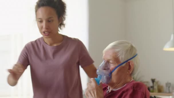 Female Caregiver Helping Elderly Man Wheelchair Put Oxygen Mask Turning — Stock Video