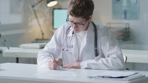 Beyaz Önlüklü Gözlüklü Genç Bir Kadın Doktorun Portresi Masaya Notlar — Stok video