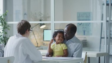 African American father and little son having health consultation with female doctor in pediatric clinic