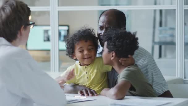 Afrikalı Amerikalı Çocuk Klinikte Kadın Çocuk Doktoruyla Konuşurken Babalarıyla Oturuyorlar — Stok video