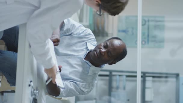 在诊所与女医生进行医疗咨询的非裔美国男子的垂直摄影 — 图库视频影像