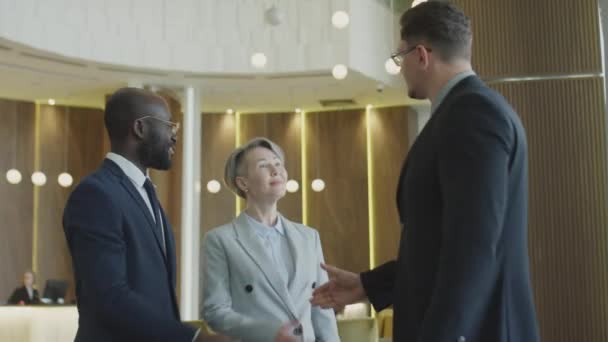 中等比例的多族裔男性和女性商业伙伴互相握手致意 并在酒店大堂进行讨论 — 图库视频影像