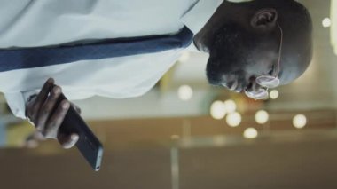 Vertical shot of African American businessman in formalwear typing on mobile phone