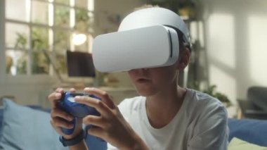 Evde sanal gerçeklik oyunu oynarken kablosuz oyun platformu kullanan VR kulaklıklı genç çocuk.