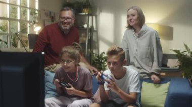 TV 'de video oyunu oynayan genç çocuklar, ailelerinin onlara tezahürat yapması ve evde ailece vakit geçirmeleri onları heyecanlandırıyor.