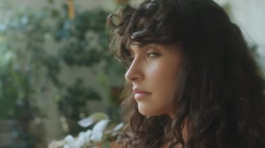 Kameraya poz veren güzel esmer kadının yakın çekimleri. Çiçeklerle gülümsüyor.