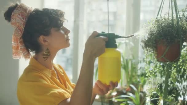 Evde Bahçeyle Ilgilenirken Bitki Yapraklarını Suyla Spreyleyen Genç Bir Kadın — Stok video