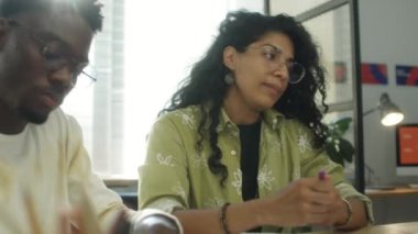 İspanyol iş kadını ofiste çok ırklı iş arkadaşlarıyla konuşuyor