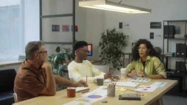 Modern ofiste birlikte çalışırken projeyi tartışan çok ırklı çalışma arkadaşları takımı