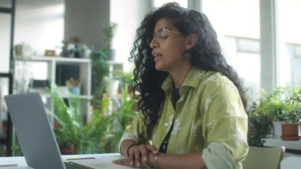 식물로 편안한 사무실에서 노트북에 통화에 말하는 즐거운 히스패닉 사업가의 — 비디오