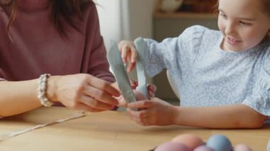 Paskalya yumurtası süsleyen küçük kızı, annesinin yardımıyla evde tatile hazırlanırken çek.