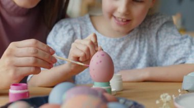 El kamerasıyla anne ve kızının boya ve fırçalarla benekli Paskalya yumurtası yaparken çekilmiş görüntüleri.