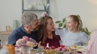 Mutlu küçük kız ve ebeveynler Paskalya yumurtasıyla oynuyorlar.