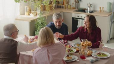 Evde Paskalya yemeği yerken kadeh tokuşturup içki içilen yüksek açılı aile fotoğrafı.