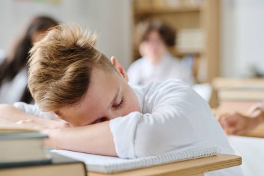 Sınıfta ders sırasında masada uyuyan yorgun öğrenci.