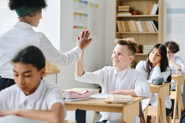 Stock image African American teacher giving high-five to student for his right answer during lesson