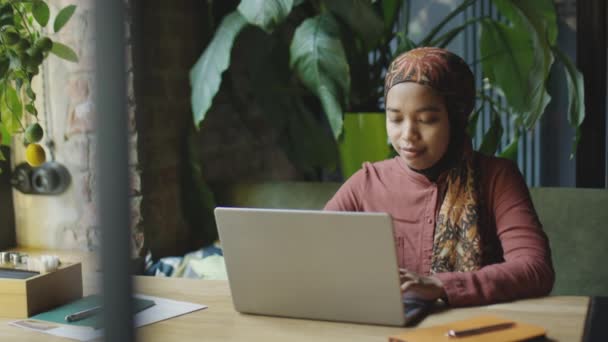 Kafedeki Masada Oturan Dizüstü Bilgisayarla Çalışan Tesettürlü Müslüman Kadını — Stok video