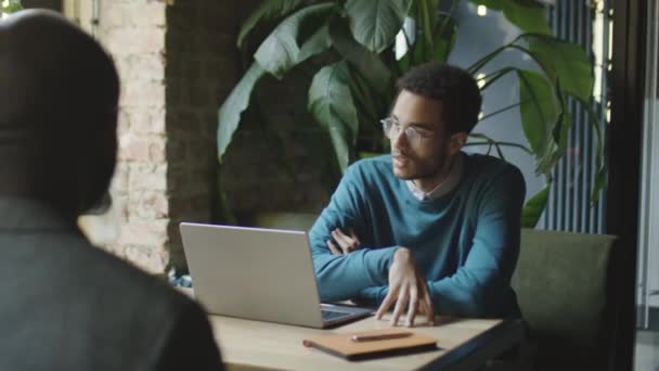 Плечом Снимок Молодого Бизнесмена Сидящего Ноутбуком Столиком Кафе Беседующего Коллегой — стоковое видео