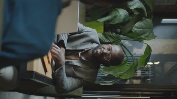 アフリカ系アメリカ人の実業家が レストランのテーブルにノートパソコンを置いて 同僚と話をする姿を垂直に描く — ストック動画