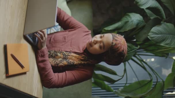 レストランのテーブルでノートパソコンでオンラインで働くヒジャブの若いイスラム教徒のビジネスマンの垂直ショット — ストック動画