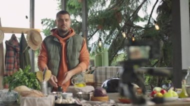 Erkek aşçının açık terasta yemek pişirirken ve dijital kamerada konuşurken çekilen fotoğraf.