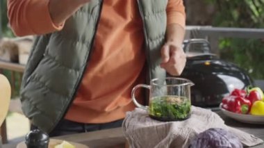 Açık terasta ev yapımı çay hazırlarken insanın cam çaydanlığa bal koyarken çekilmiş el kamerası görüntüsü.