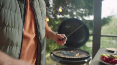 Açık terasta bbq pişirirken başka bir bıçakla keskinleştirilmiş erkek aşçının elleri.
