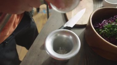 Mutfak masasında yemek hazırlarken deniz tuzu ve baharatları havan topuzuyla ezen bir adamın yüksek açılı görüntüsünü yakın çekim yapın.