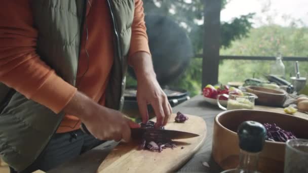 木製の板にナイフで赤いキャベツを切った男のクロップショット Bbqグリルで屋外テラスで調理中 — ストック動画