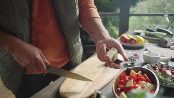 男厨师切茄子和在室外平台上烹调食物时将蔬菜放入碗中的双手切碎的照片 — 图库视频影像