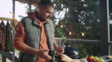 Yemek blogcusunun kamerada konuştuğu ve terasta yemek pişirirken ciabatta ekmeği kestiği görüntüyü eğ