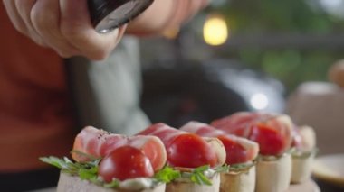 Domuz pastırması, roka ve domatesli karabiber ezen erkek şefin yakın plan çekimleri.