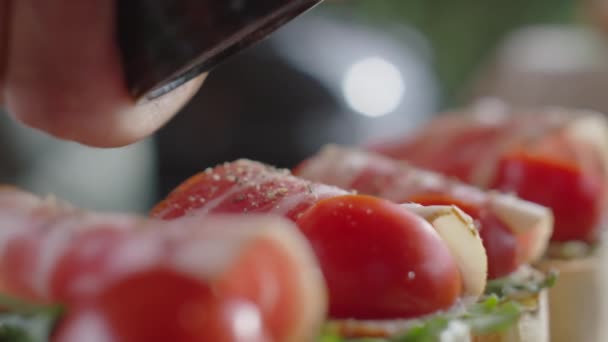 ベーコン アルギュラ トマトで新鮮な地面の黒唐辛子をブロシェッタスに追加する最高のクローズアップショット — ストック動画