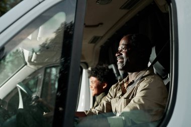 Mutlu Afrikalı Amerikalı baba oğluyla minibüsün yanından geçiyor.