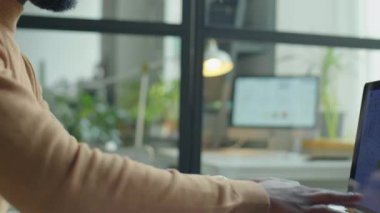 Ofisteki mali raporlar üzerinde çalışırken Afrikalı Amerikalı iş adamının bilgisayarda daktilo yazarken çekilmiş el kamerası görüntüsü.