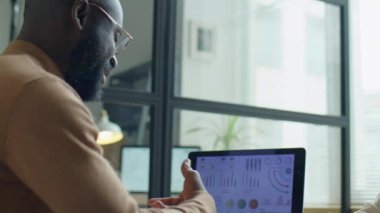 Afrika kökenli Amerikalı iş adamı ofisinde buluşurken neşeli beyaz kadın meslektaşıyla konuşuyor ve tokalaşıyor.