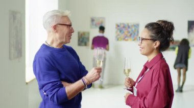 Üst düzey bir adam ve genç bir kadının sanat galerisinde şampanya içerek sergiyi tartışırken belini kaldır.
