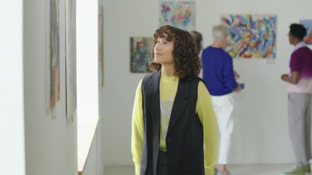 現代美術ギャラリーを訪問しながら カーリーヘアを観察する若い女性のショットをウエスト — ストック動画