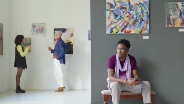 Εντοπισμός Στιγμιότυπο Του Νεαρού Αφροαμερικανού Άνδρα Κρατώντας Τηλέφωνο Και Κάθεται — Αρχείο Βίντεο