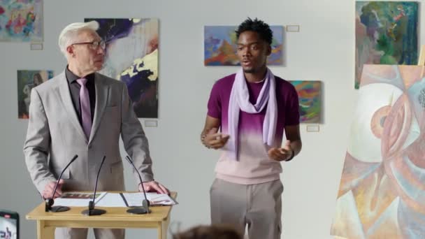 Młody Afroamerykanin Prezentuje Obraz Publiczności Sceny Sprzedając Aukcji Sztuki — Wideo stockowe