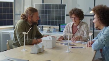 Ofis toplantısında ekip halinde çalışırken yenilenebilir enerji projesini tartışan çok ırklı mühendisler grubu