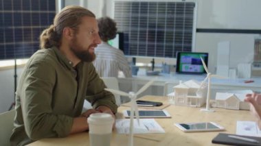 Modern ofiste çalışma saatlerinde yenilenebilir enerji projesini tartışan iki erkek mühendis.
