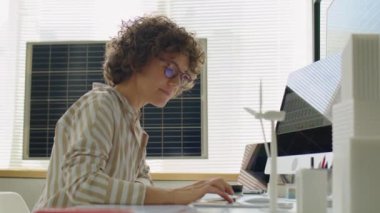 Kadın yenilenebilir enerji geliştirici. Bilgisayarda yazıyor ve güneş pilleriyle çalışırken dijital tablet kullanıyor.