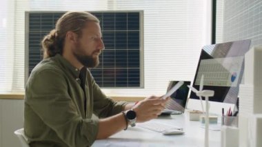 Dijital tablet üzerinde çalışan yenilenebilir enerji geliştiricisinin yan görünümü ve ofiste güneş pilleri ile bilgisayar kullanımı