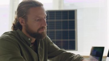 Yenilenebilir enerji mühendisinin yakın plan çekimi. Dijital tablet ve güneş panelleri olan bilgisayar üzerinde çalışıyor.