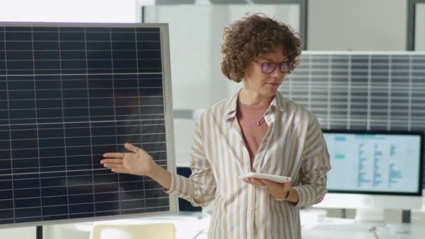 デジタルタブレットを保有する女性再生可能エネルギー開発者の中型ショット オフィスミーティング中にプレゼンテーションを行いながらソーラーパネルを指す — ストック動画