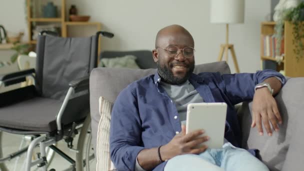Afro Americano Com Deficiência Descansando Sofá Perto Cadeira Rodas Conversando — Vídeo de Stock