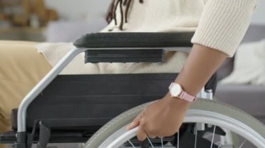 Özürlü, tanınmayan siyahi bir kadının, evinde ilerlerken el tekerlekli sandalyesini öne iterken görüntüsü.